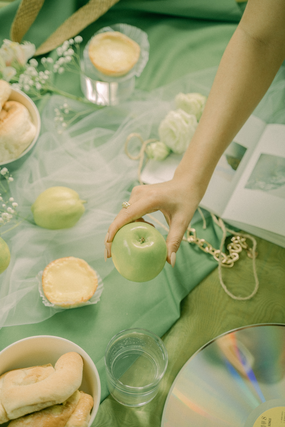 Hand with Green Apple above Various Materials on Green Fabric